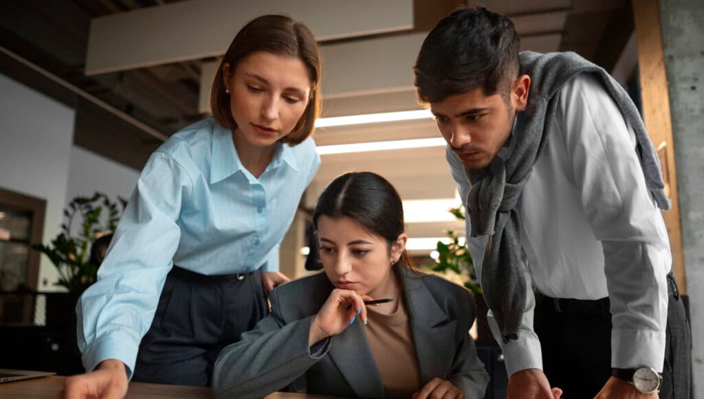 Three business professionals analyzing security compliance reports and graphs at an office table.